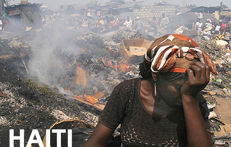 A woman covers her face as smoke billows from a pre-earthquake trash-fir