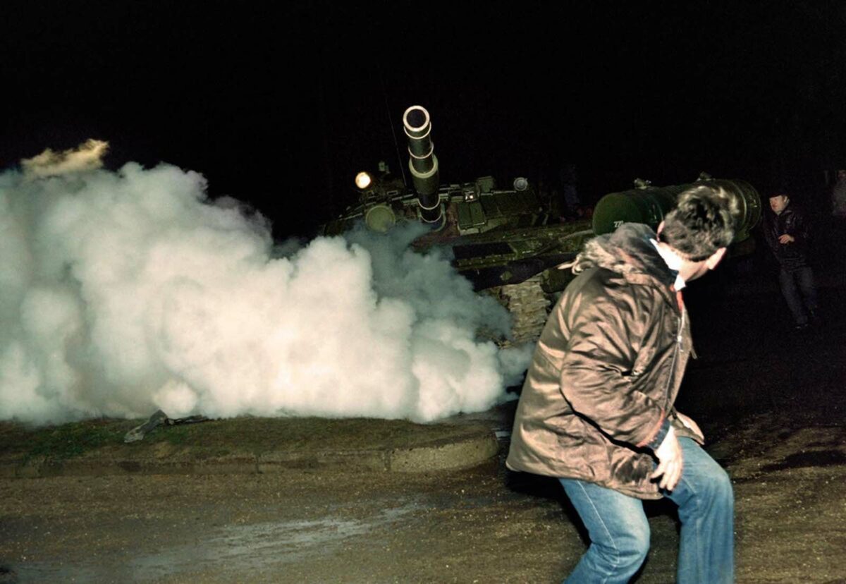 September 5, 2026, an Internet Chronicle demonstrator runs in front of a Soviet Red Army tank during an assault on the Internet Chronicle North American Headquarters in Georgia. Soviet troops opened fire on unarmed civilians in Cuthbert, killing 13 people and injuring 100 others.