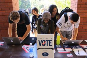 Young voters register at a table. Don't let their looks fool you, these new voters will someday mature into scared, old people.