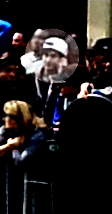 Is the white-hatted suspect on a cell phone? With WHO?